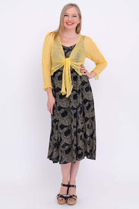 Model wearing the Shauna midi dress and a yellow cardigan, posing hand on hip