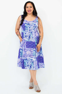 Woman showing pockets a blue and purple patchwork print dress