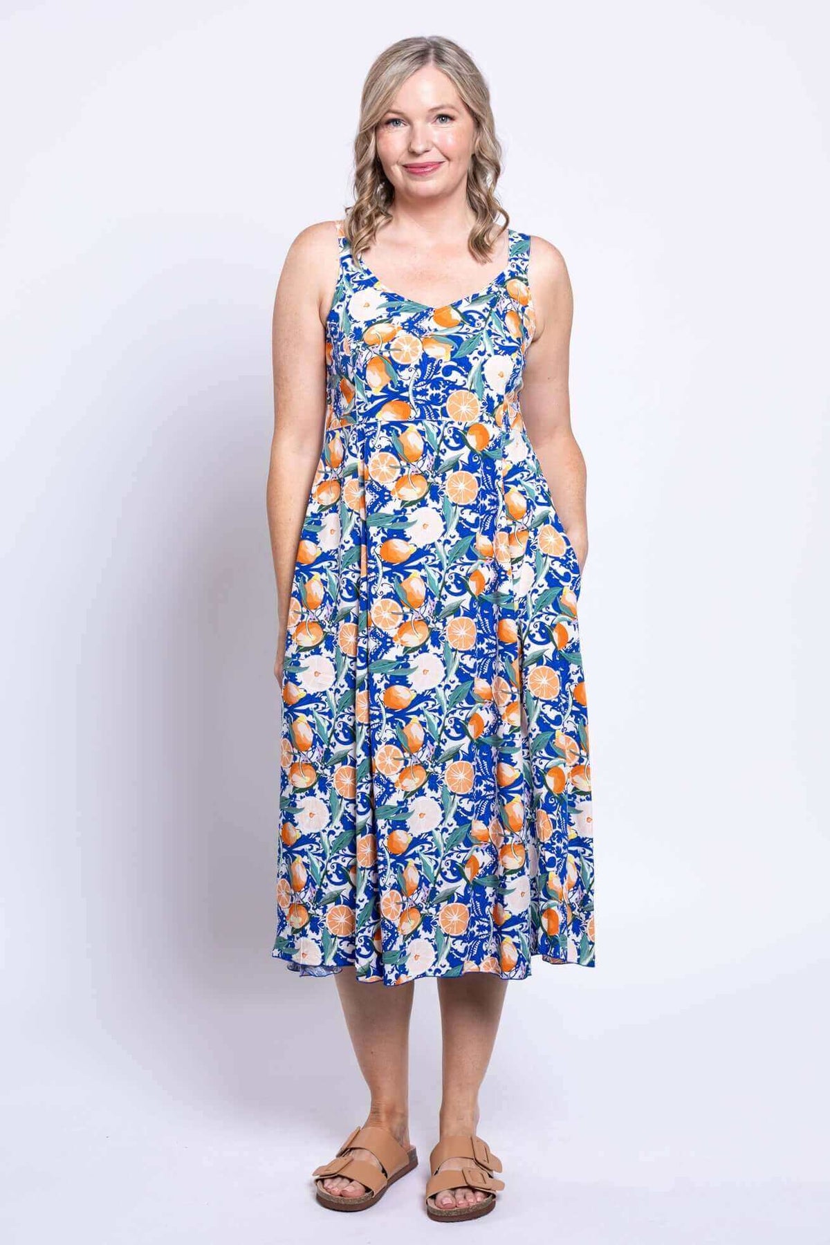 Woman showing the side pockets of a sleeveless citrus floral print dress