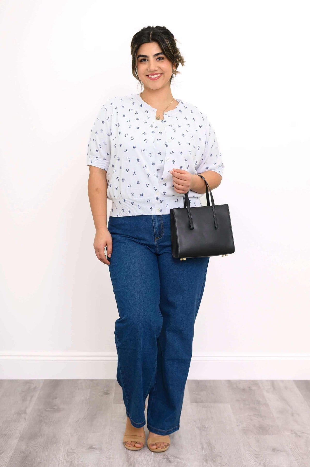 Woman in Shen nautical cardigan holding black handbag and wearing jeans