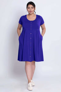Woman showing the functional pockets of a royal blue empire waist dress