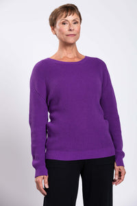 Side-angled view of a woman in a purple shaker stitch sweater
