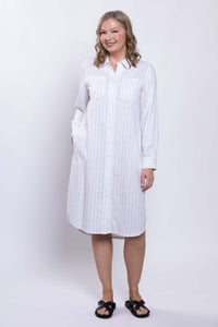 Side-angled view of a woman in a white striped shirt dress with pockets