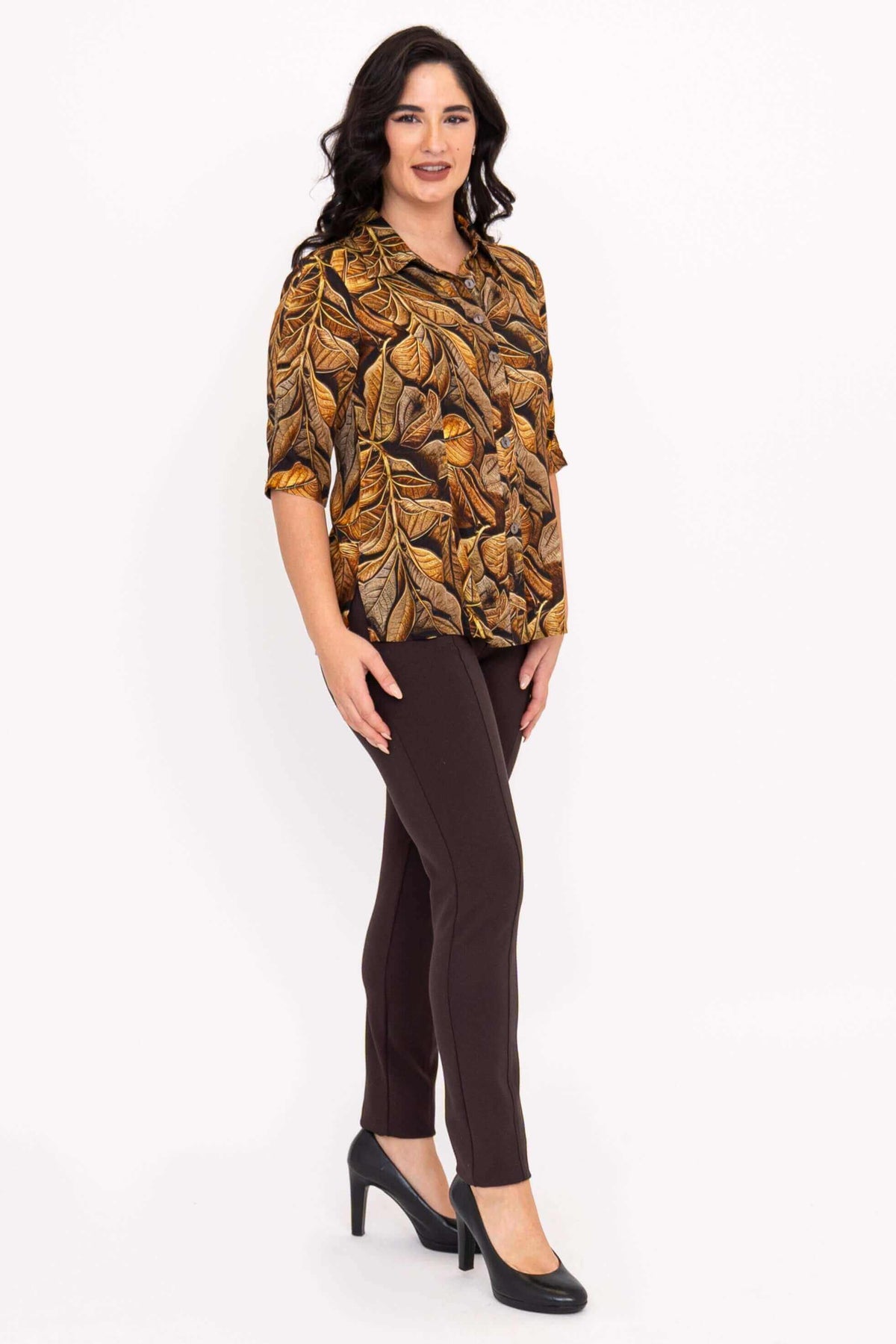 Woman in leaf print blouse and brown pants, side-front angle