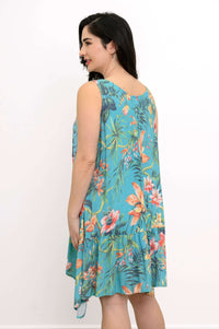Side back view of woman in turquoise floral dress showing ruffle detail and relaxed fit