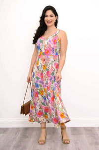 Side front view of a woman twirling in a floral maxi dress with handbag