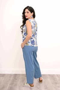 Woman in blue botanical print tank top and pants, showing side and back of outfit