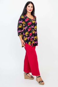 Side view of model wearing a black top with pink and yellow chrysanthemum motifs and red pants