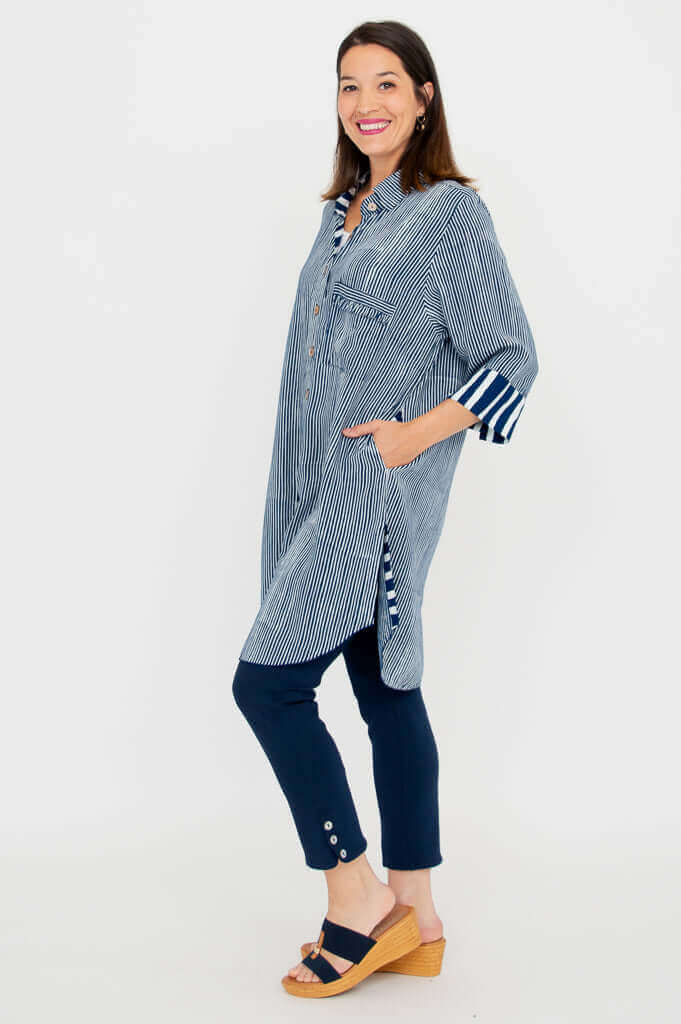 Side angle of a woman in a blue striped oversized tunic shirt with 3/4 sleeves