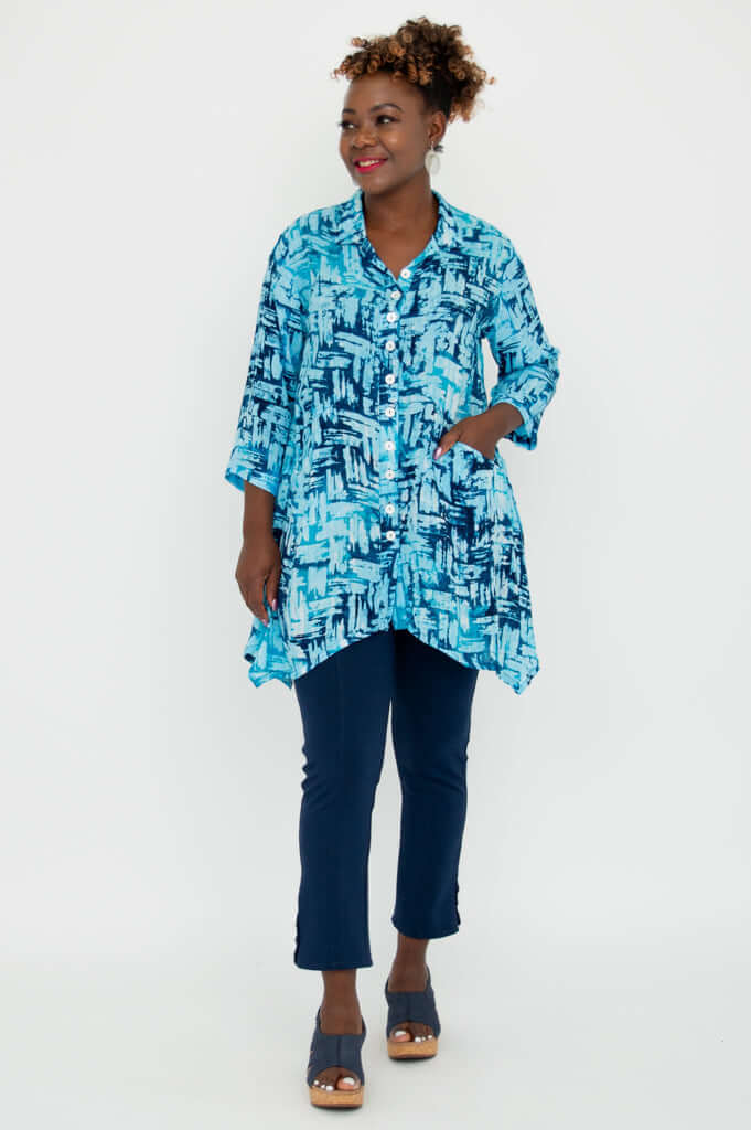 Side angled view of woman in turquoise brushstroke Laney Blouse and navy pants