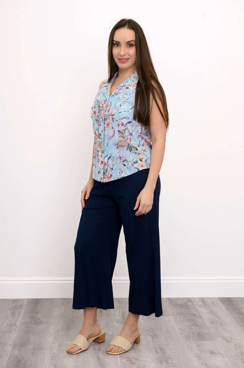 Full-length side angle of model in sleeveless floral shirt and navy pants on a light background