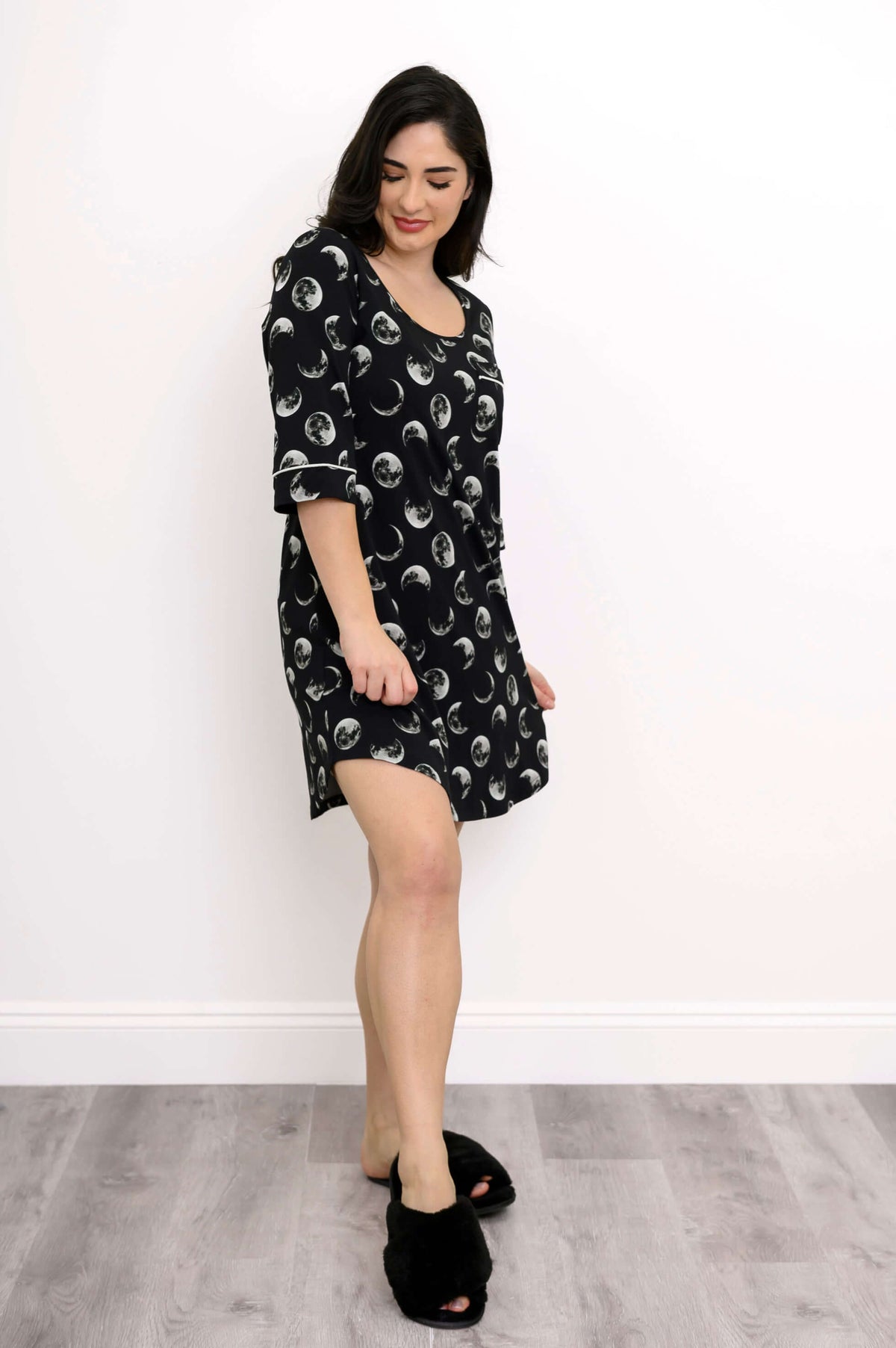 Side angle view of woman in black bamboo sleepshirt featuring moon prints