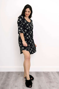 Side angle view of woman in black bamboo sleepshirt featuring moon prints