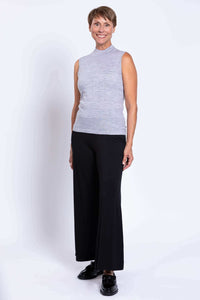 Side view of woman in grey sleeveless mock neck sweater with black pants