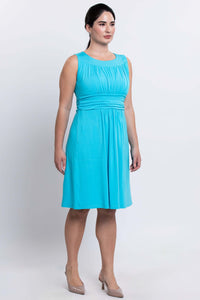 Angled side view of woman in aqua blue ruched bodice knee-length dress