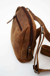 Side angled close-up of the brown leather crossbody bag showing sturdy construction and zippers