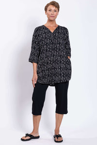 Three-quarter view of a woman in a black tunic with side pockets and white pattern