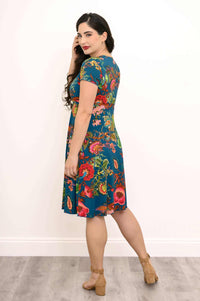 Woman turning to the side, modeling a teal floral bamboo wrap dress