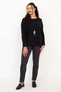 Model standing and looking to the side in black Merino sweater and gray pants