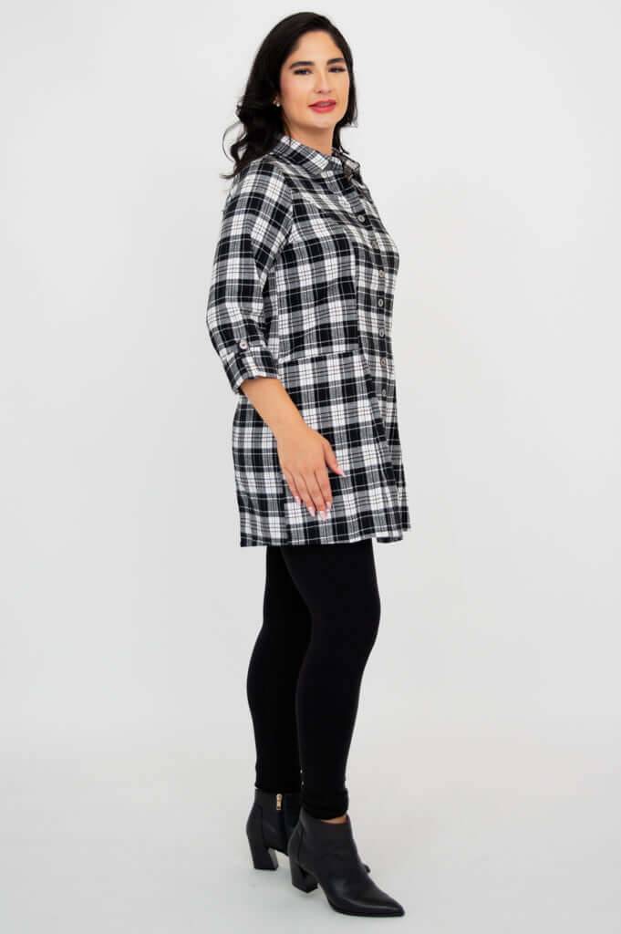 Side profile of model in black and white plaid flannel tunic and black leggings