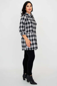 Side profile of model in black and white plaid flannel tunic and black leggings