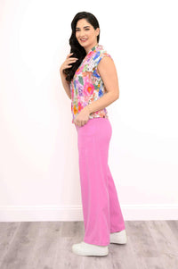 Side profile of a woman in a colorful floral tank top and bright pink pants