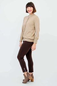 Side view of a woman in a beige button-up cardigan and brown slim-fit pants