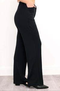 Side profile of black high-waisted trousers showing pocket and relaxed fit
