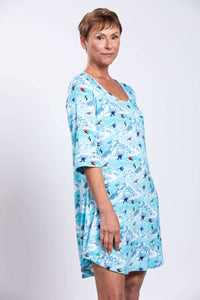 Side view of woman in blue sleepshirt featuring skiing design and piping detail