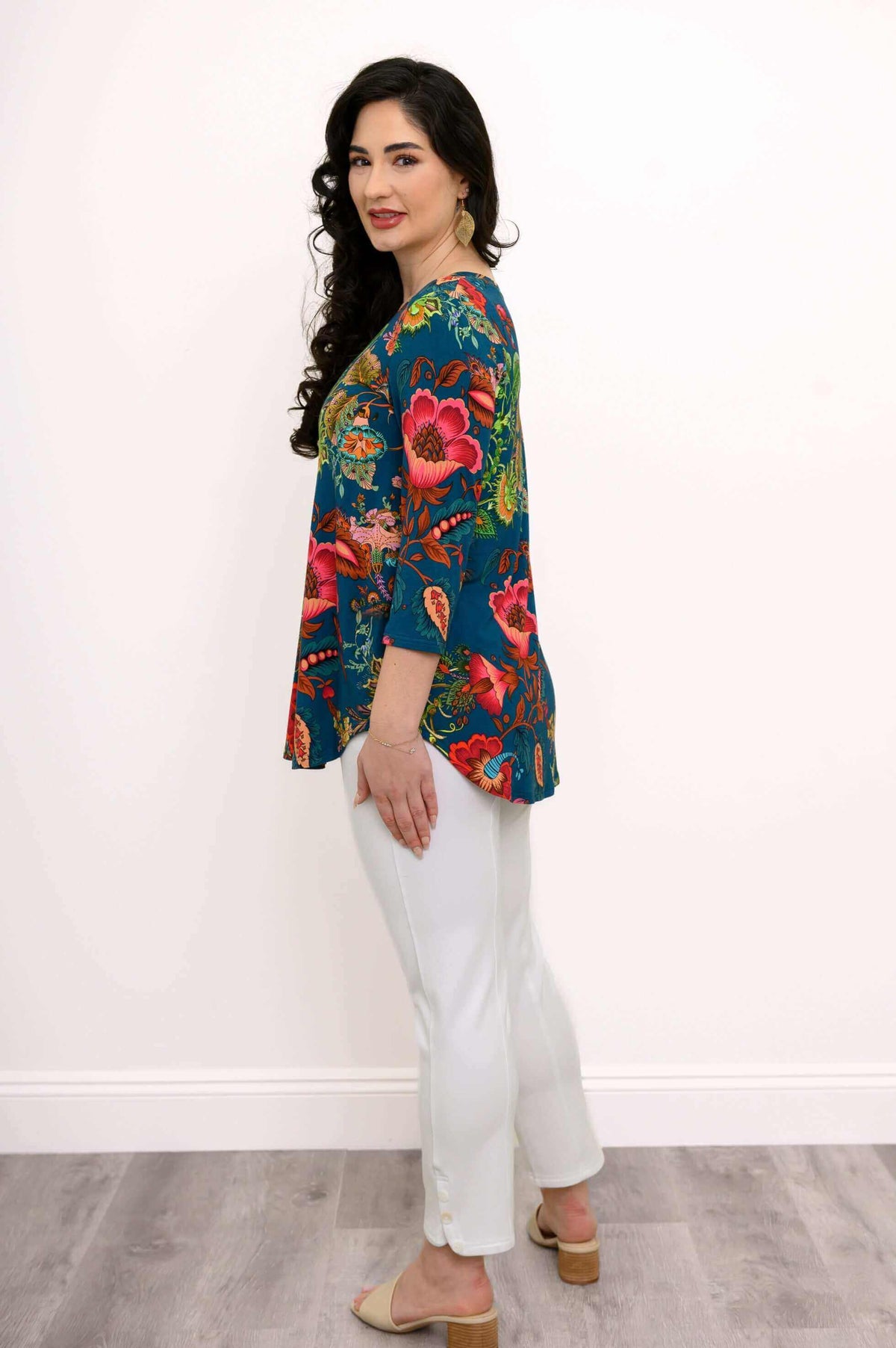 Side profile of a woman in a blue floral top with white pants and heeled sandals