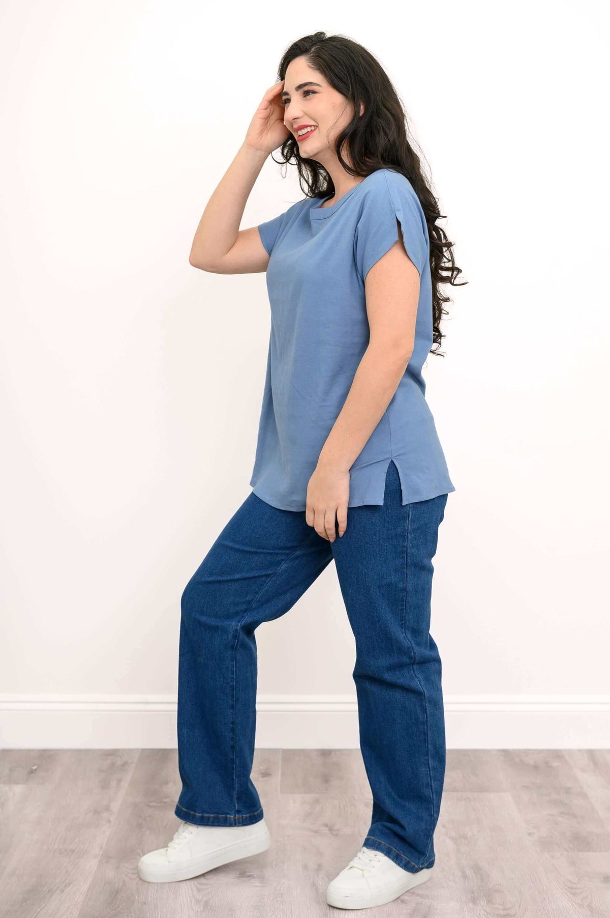 Side view of woman in blue linen blend tee with cap sleeves and side slit