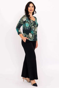 Side view of model in green floral top and black pants with hand in pocket