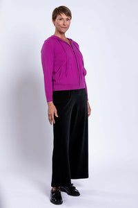 Side profile view of a woman wearing a magenta zip up hoodie displaying pocket and sleeve fit.