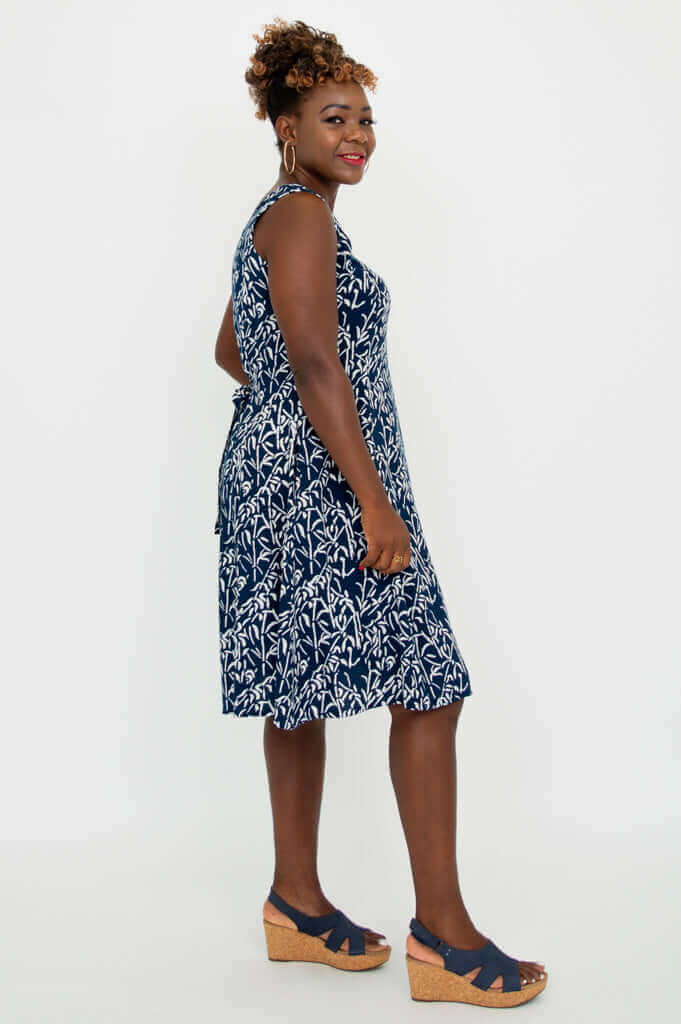 Side view of model in a navy and white sleeveless summer dress with wedge sandals