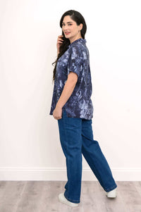 Woman showing side profile of navy floral blouse with rolled sleeves and jeans