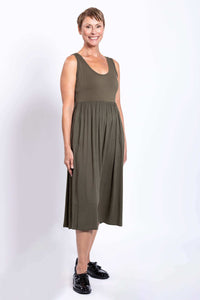 Side view of woman in olive empire waist midi dress and black shoes