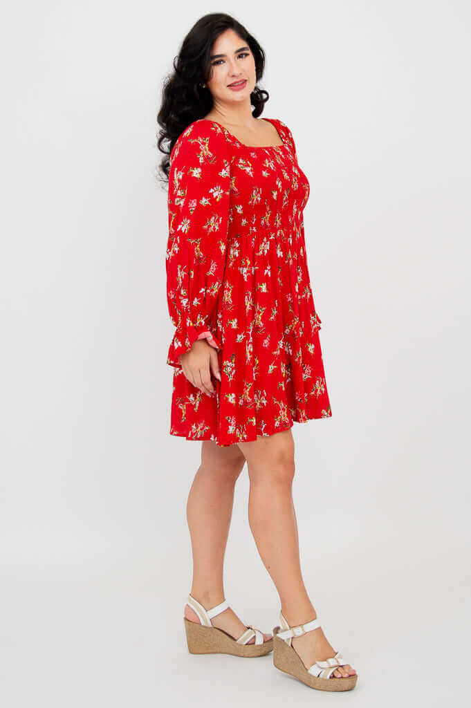 Side view of woman in red ditsy floral dress with ruffled long sleeves and square neckline