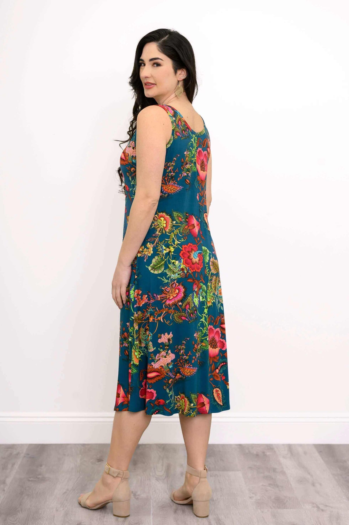 Woman showing side view of teal floral tank dress with bright floral print