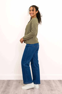 Side view of woman modeling a green cable knit cashmere cardigan and blue jeans