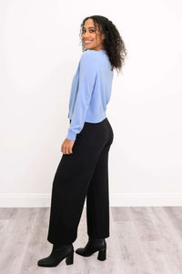 Side view of a woman in a light blue cashmere cardigan and black pants, smiling