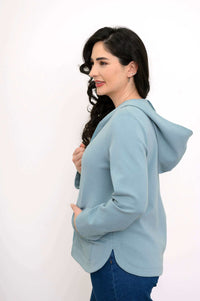 Side view of woman in a light blue hooded zip-up jacket with tailored seams
