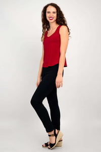 Side view of woman in red tank top and black pants, smiling