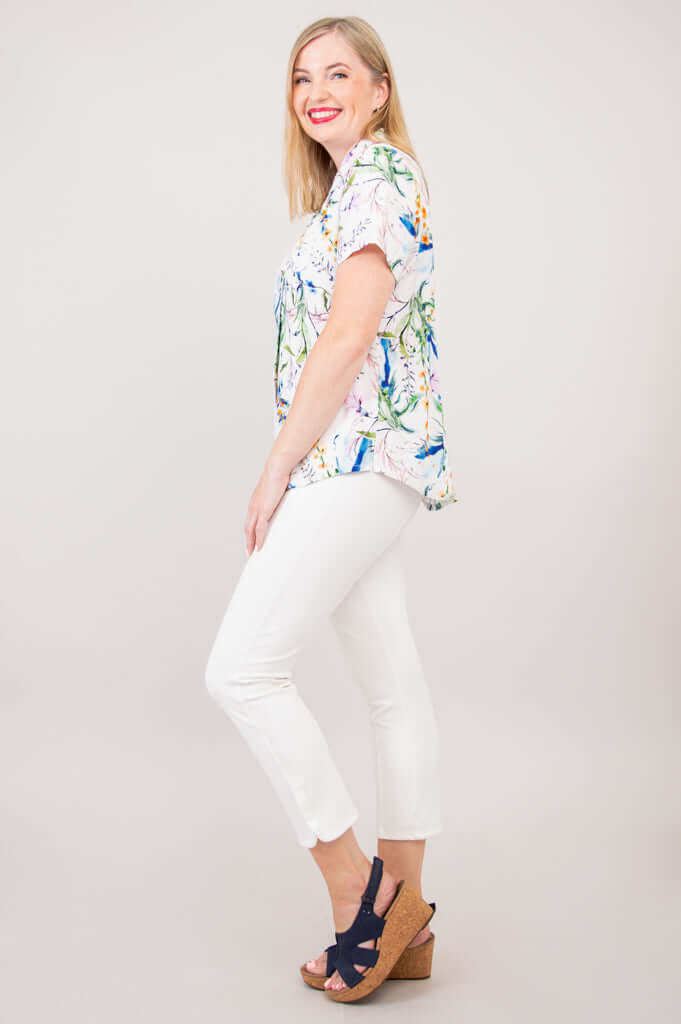 Woman wearing the floral shirt with white pants and navy wedges, side profile