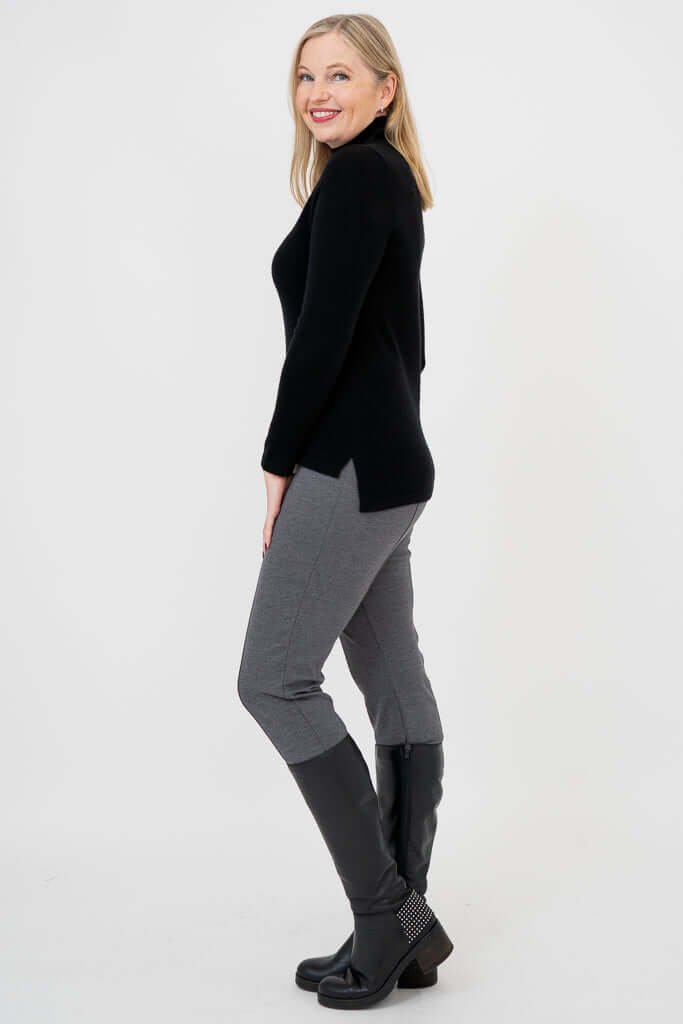 Side profile of woman in black mock neck sweater showing hi-lo hemline