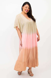 Woman in a V-neck pastel ombre maxi dress standing sideways and smiling
