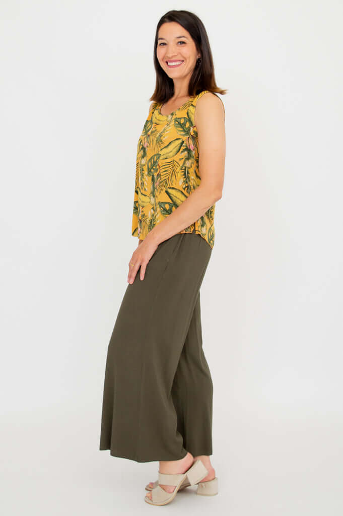 Woman side view of yellow tropical print sleeveless tank top and green wide-leg pants