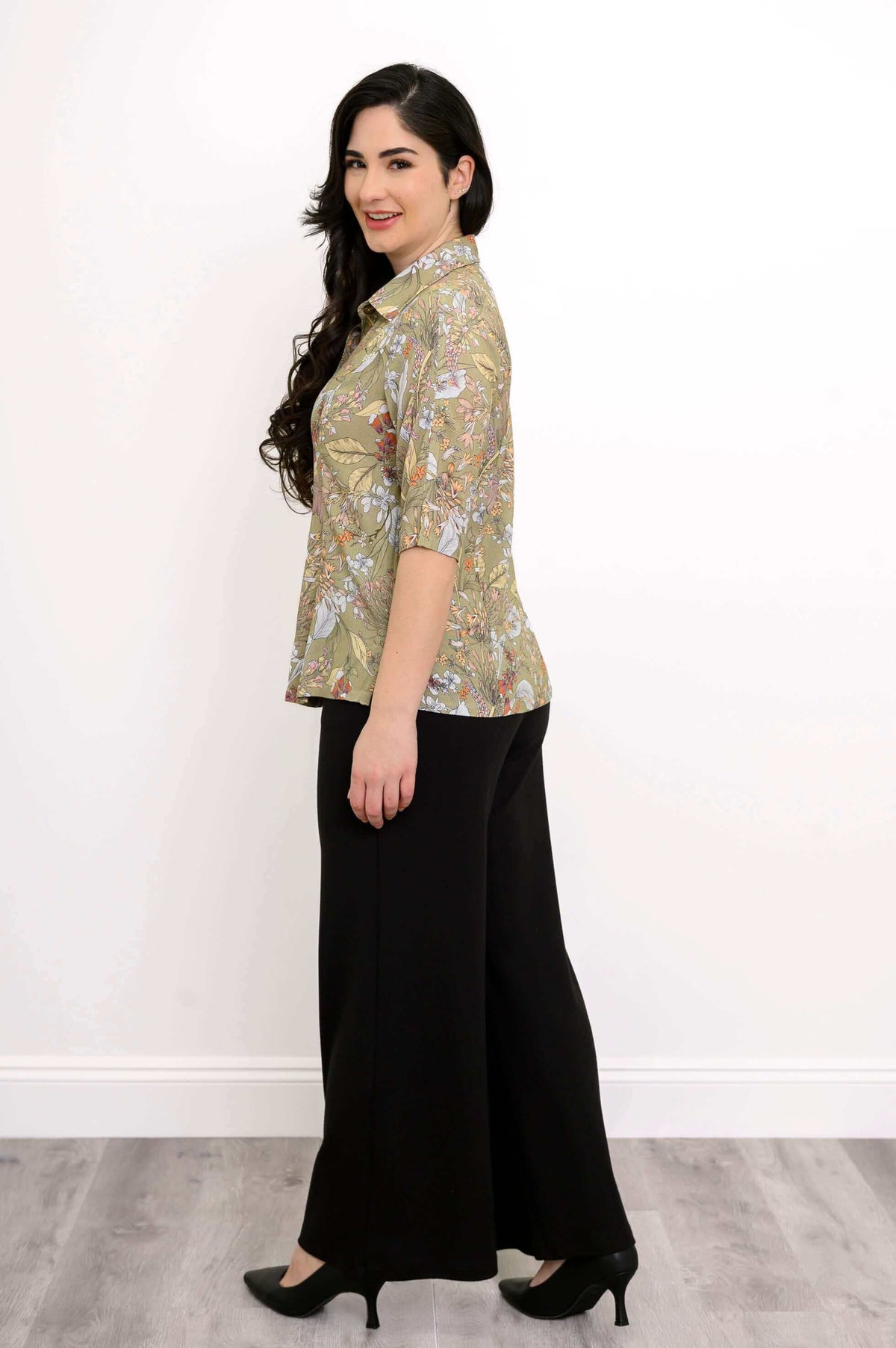 Side view of model in green floral bamboo linen blouse and black wide-leg pants