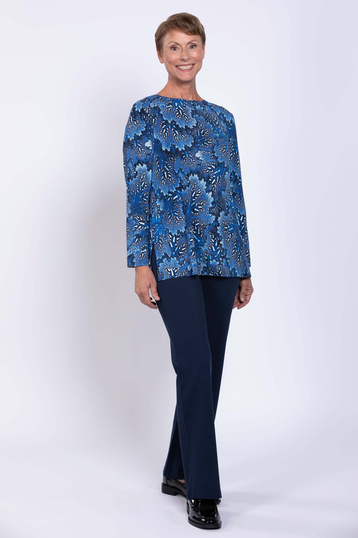 Side view of woman smiling in blue botanical Margie top and navy pants
