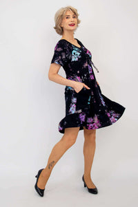 Side view of woman showing movement in black floral dress with ruffle hem