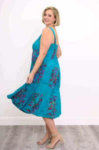 Side view of woman twirling in an aqua blue floral sleeveless midi dress